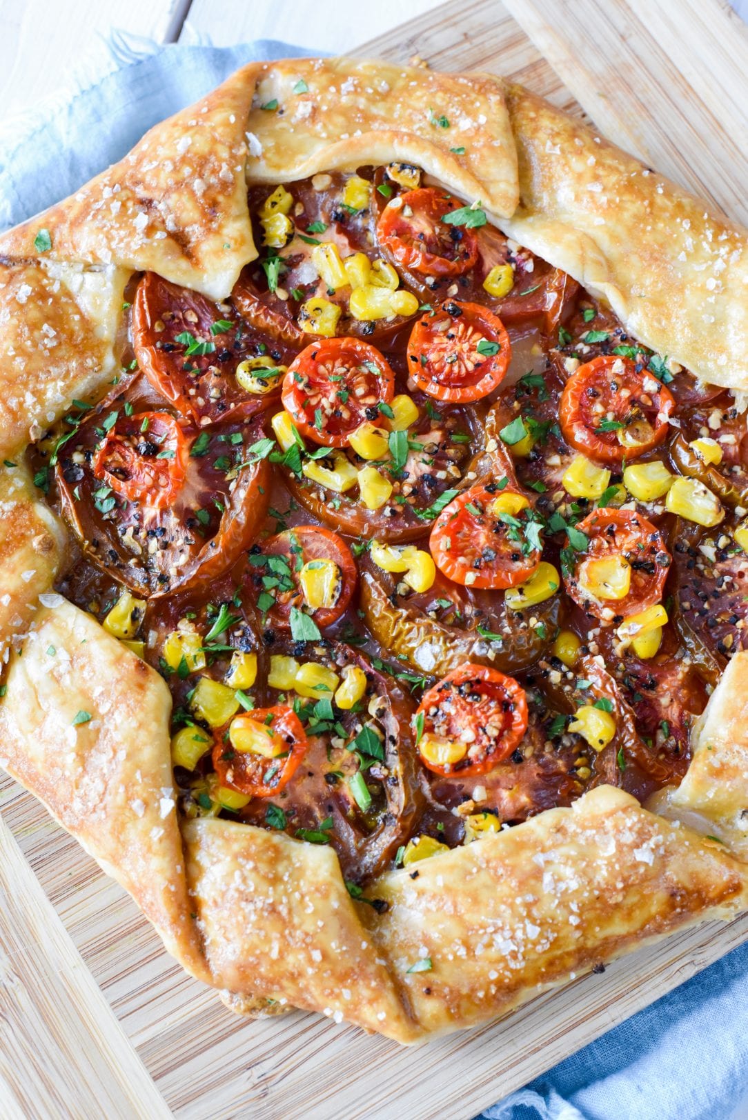 galette with roasted corn and tomatoes sitting on a cutting board