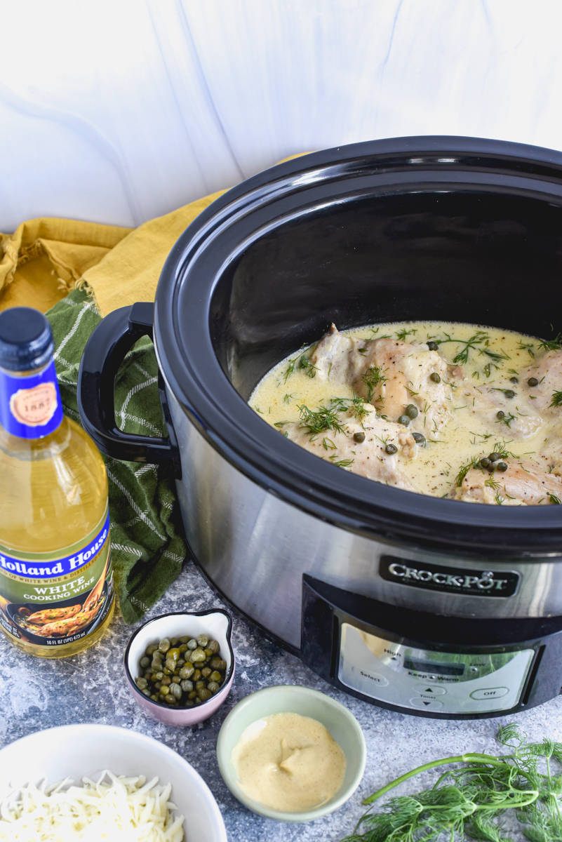 chicken dijon sitting in slow cooker with cheese, capers, and dijon mustard in dishes