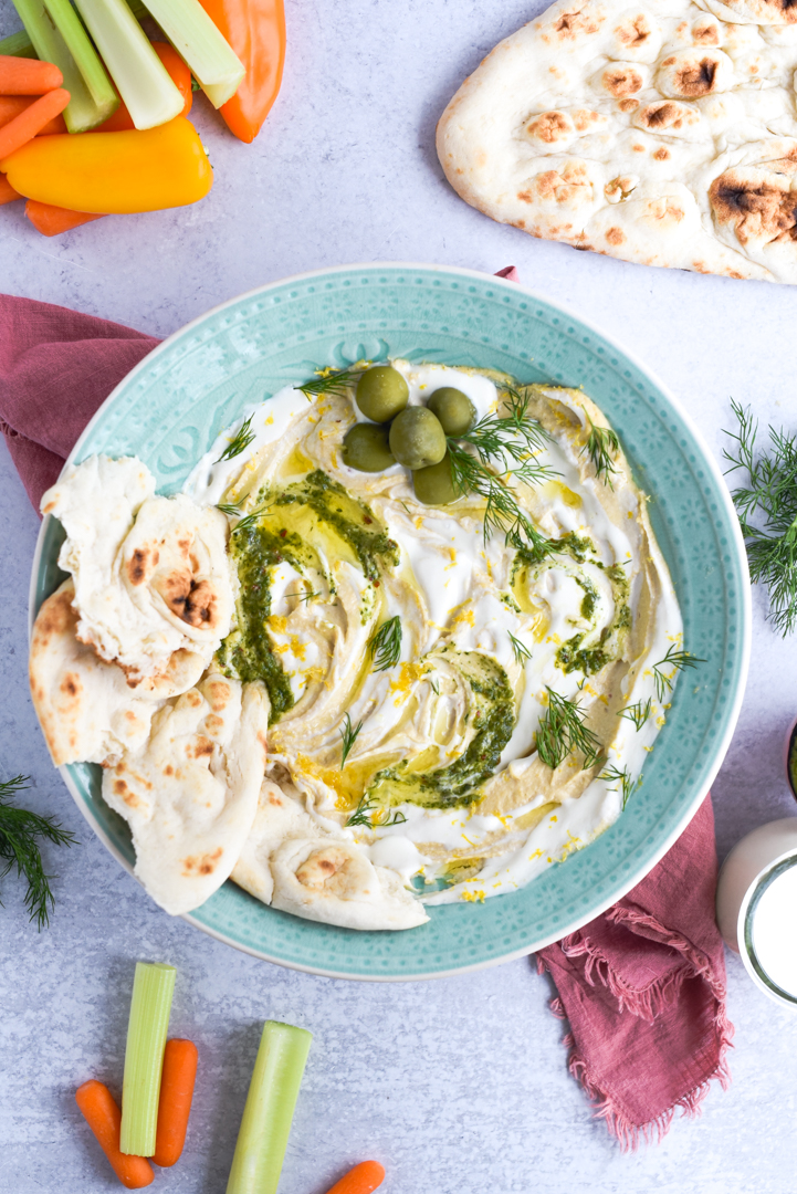 hummus in a bowl with whipped feta and olives, pita, olive oil, as garnish