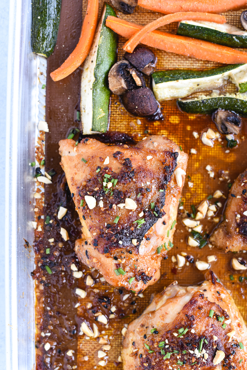 easy sheet pan peanut chicken on a roasting pan with vegetables