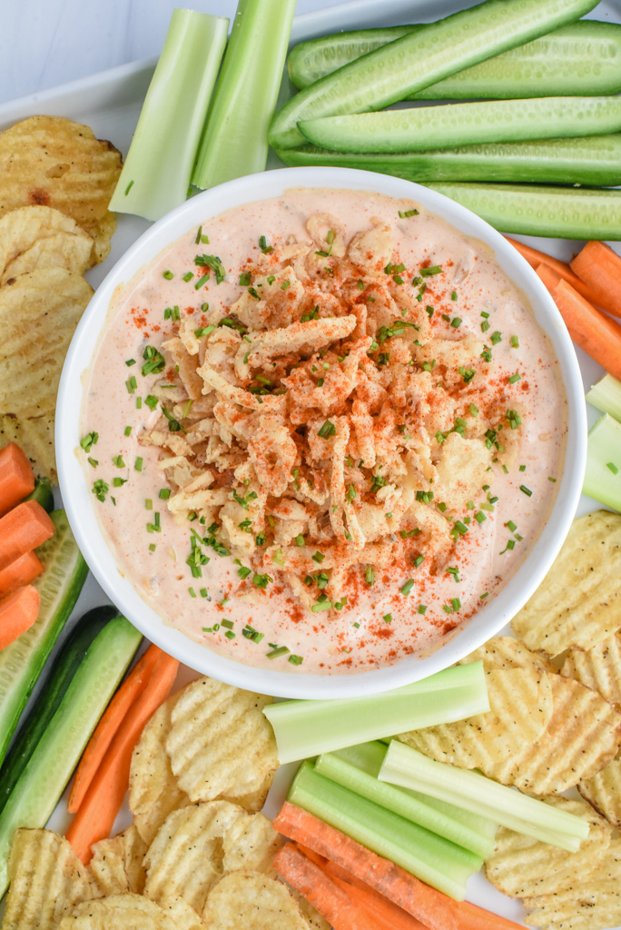 bloomin' onion dip in a serving dish with veggies and chips on a plate